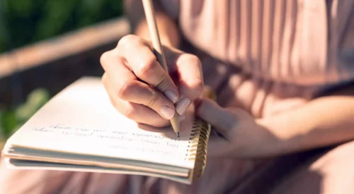 Femme écrivant dans un carnet lors d'un moment de réflexion et d'introspection