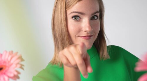 Femme souriante pointant vers l’objectif, incarnant la réussite personnelle et l’équilibre de la maman d’aujourd’hui