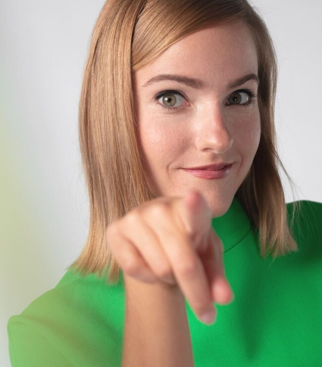 Femme souriante pointant vers l’objectif, incarnant la réussite personnelle et l’équilibre de la maman d’aujourd’hui