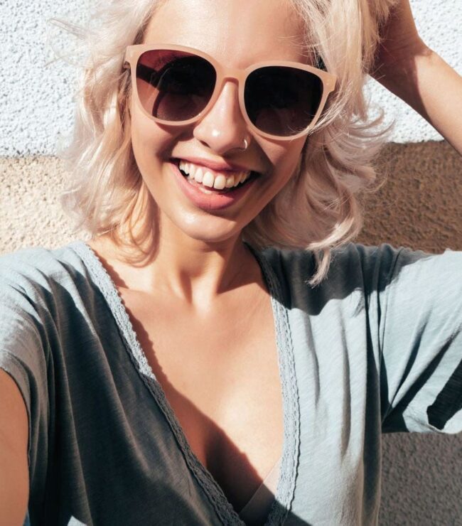 Femme souriante aux cheveux blonds lumineux, coiffure tendance printemps été 2026, style naturel et summer vibes