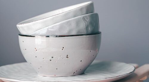 Vaisselle en porcelaine artisanale aux tons clairs, empilée sur une assiette, pour une décoration intérieure élégante et minimaliste