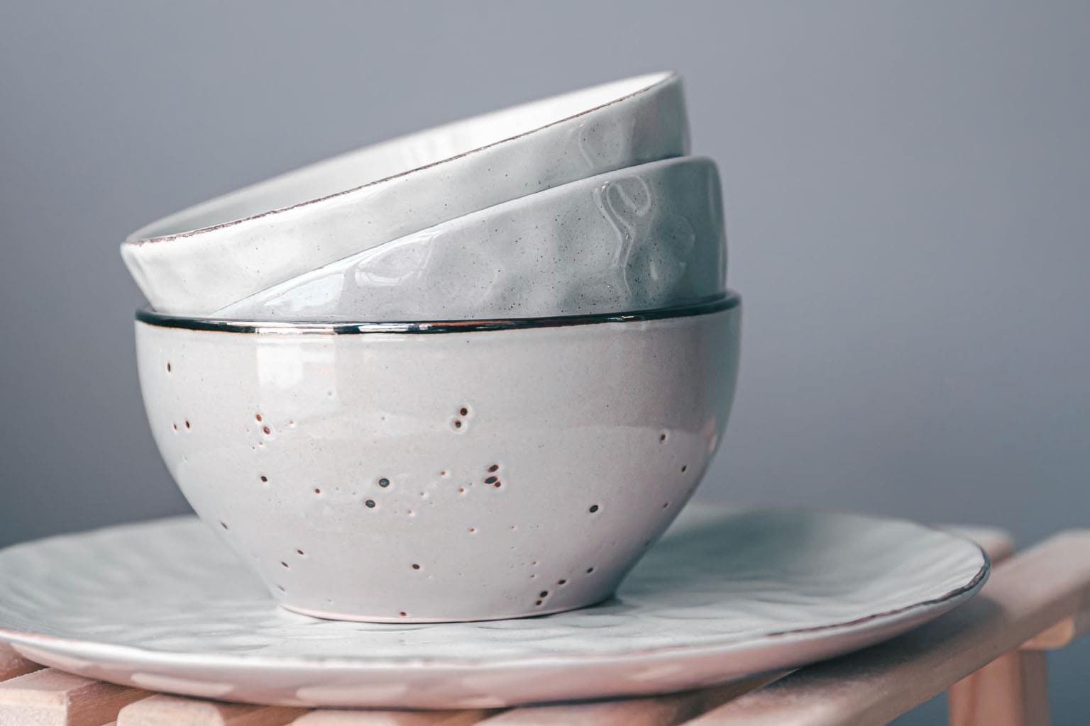 Vaisselle en porcelaine artisanale aux tons clairs, empilée sur une assiette, pour une décoration intérieure élégante et minimaliste