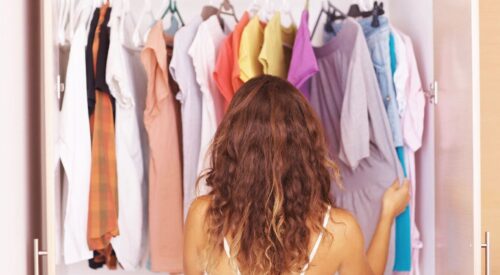 Femme de 40 ans devant son dressing en train de choisir sa tenue, tri de garde-robe et sélection mode femme active – Be by Maman