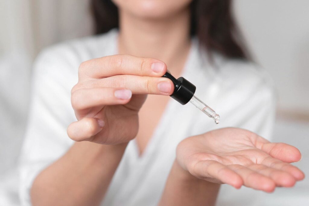 femme 40 ans routine skincare serum anti age teint parfait peau jeune bebymaman Femme appliquant un sérum sur la main.