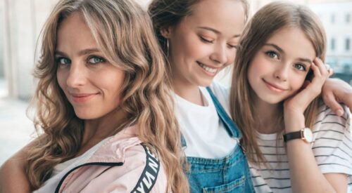 Alt (riche SEO) Maman quadra souriante entourée de deux jeunes femmes, illustration de la transmission et de l’équilibre entre féminité, famille et épanouissement après 40 ans.