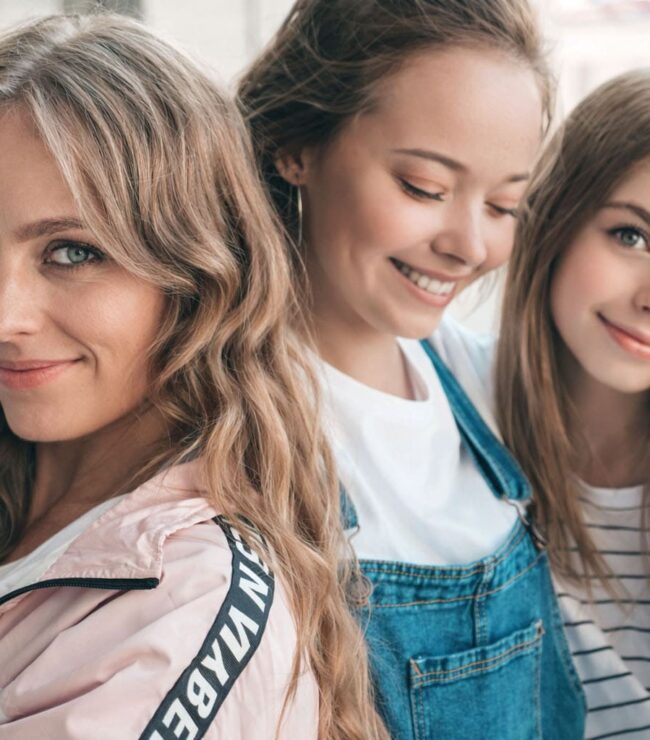 Alt (riche SEO) Maman quadra souriante entourée de deux jeunes femmes, illustration de la transmission et de l’équilibre entre féminité, famille et épanouissement après 40 ans.