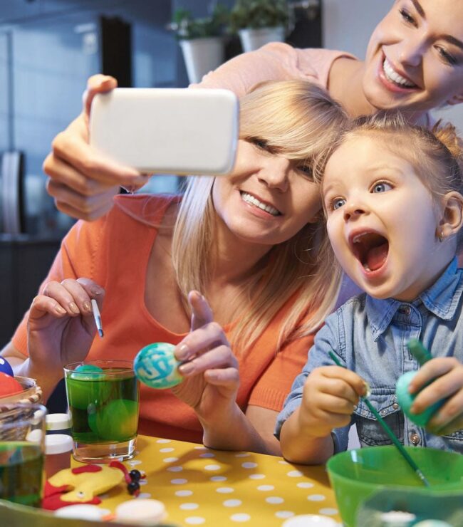 Activité de Pâques en famille avec enfants décorant des œufs colorés autour d’une table