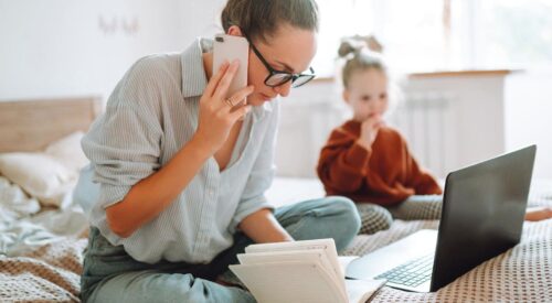 maman en télétravail avec ordinateur portable et téléphone pendant que son enfant joue à côté charge mentale working mum quotidien