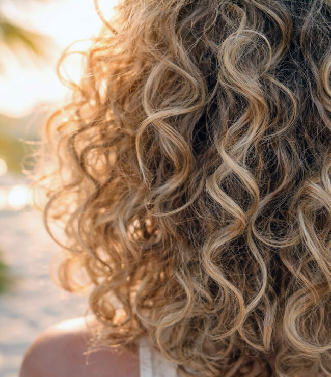 boucles naturelles en gros plan au soleil coiffure été cheveux bouclés