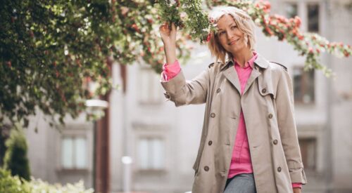 Femme souriante profitant du printemps sous un arbre en fleurs, incarnation de la slow attitude maman au mois de mai