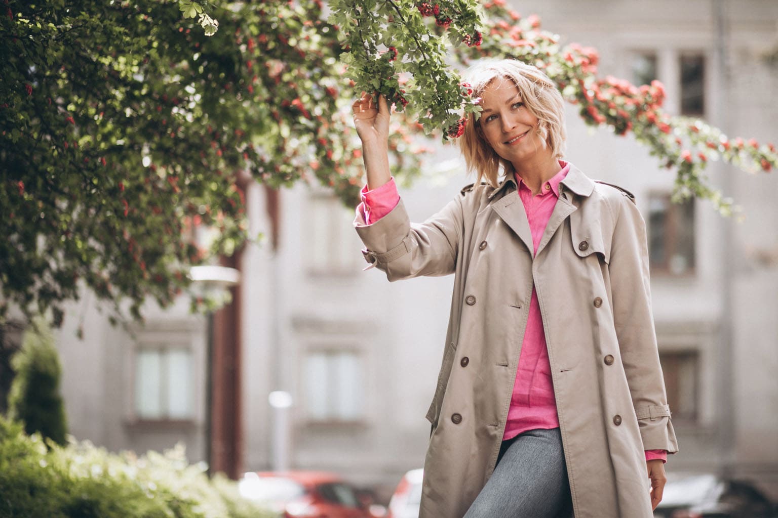 Femme souriante profitant du printemps sous un arbre en fleurs, incarnation de la slow attitude maman au mois de mai