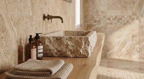Salle de bain en travertin avec vasque en pierre brute et plan en bois naturel