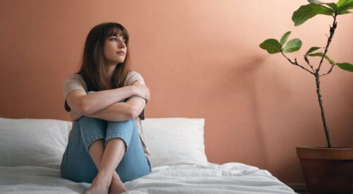 femme assise sur un lit regardant au loin moment de réflexion slow maman équilibre personnel