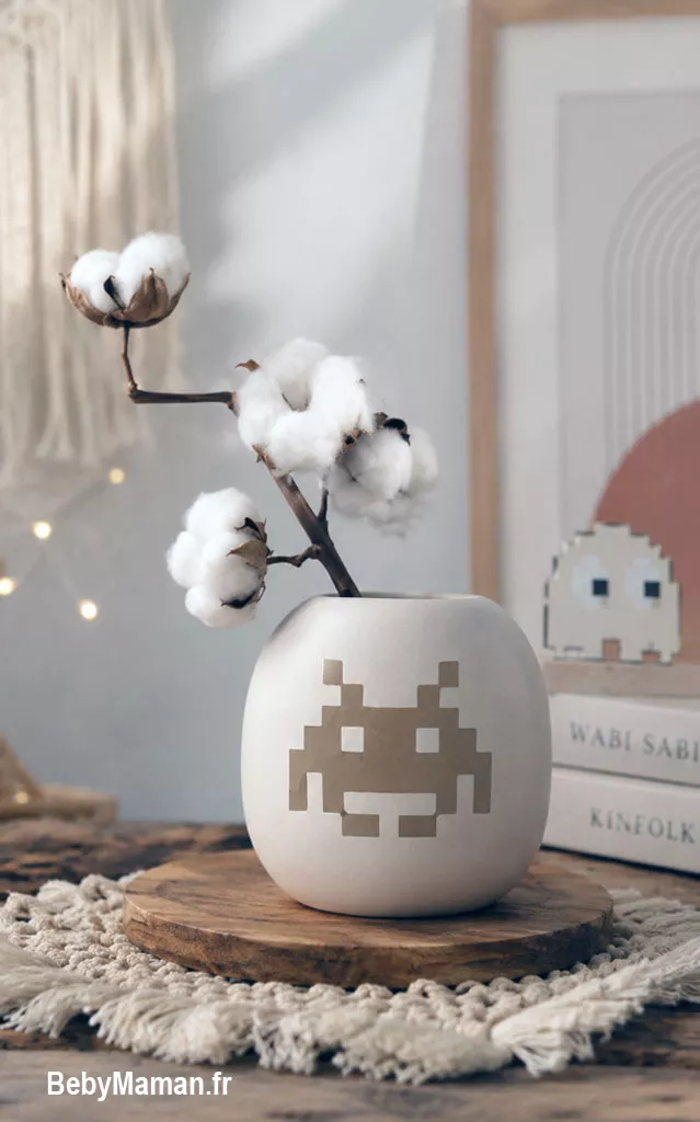 vase jeux video decoration boheme geek chic papa maman maison bebymama Vase blanc avec motif Space Invaders posé sur un plateau en bois et décoré de branches de coton dans une décoration minimaliste.