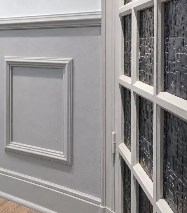 Boiseries à moulures et porte vitrée ancienne peintes en Gazelle de Dulux Valentine, avec un mur blanc au-dessus.